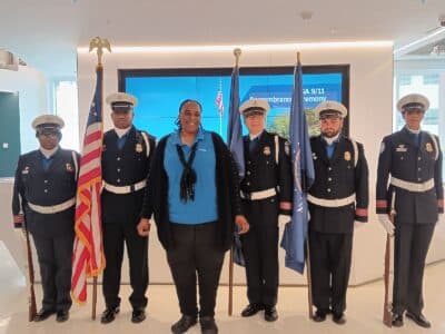 Lisa is standing with two Coast Guardsmen on the left and three on the right. Three of the Coast Guardsmen are holding flags.